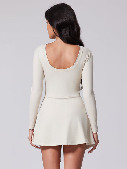 Woman wearing a white dress with long sleeves on a plain background