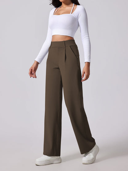 Person wearing a white long-sleeve top and brown wide-leg pants on a light gray background