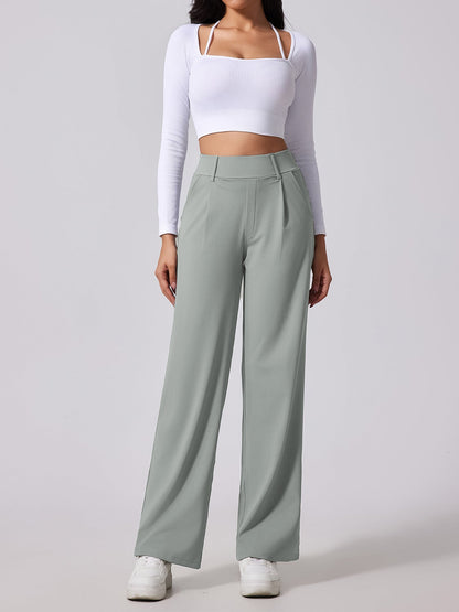 Person wearing a white long-sleeve crop top and light gray wide-leg pants on a plain background