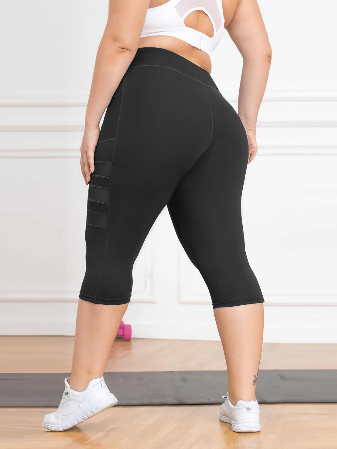 Person wearing black capri leggings with a white background