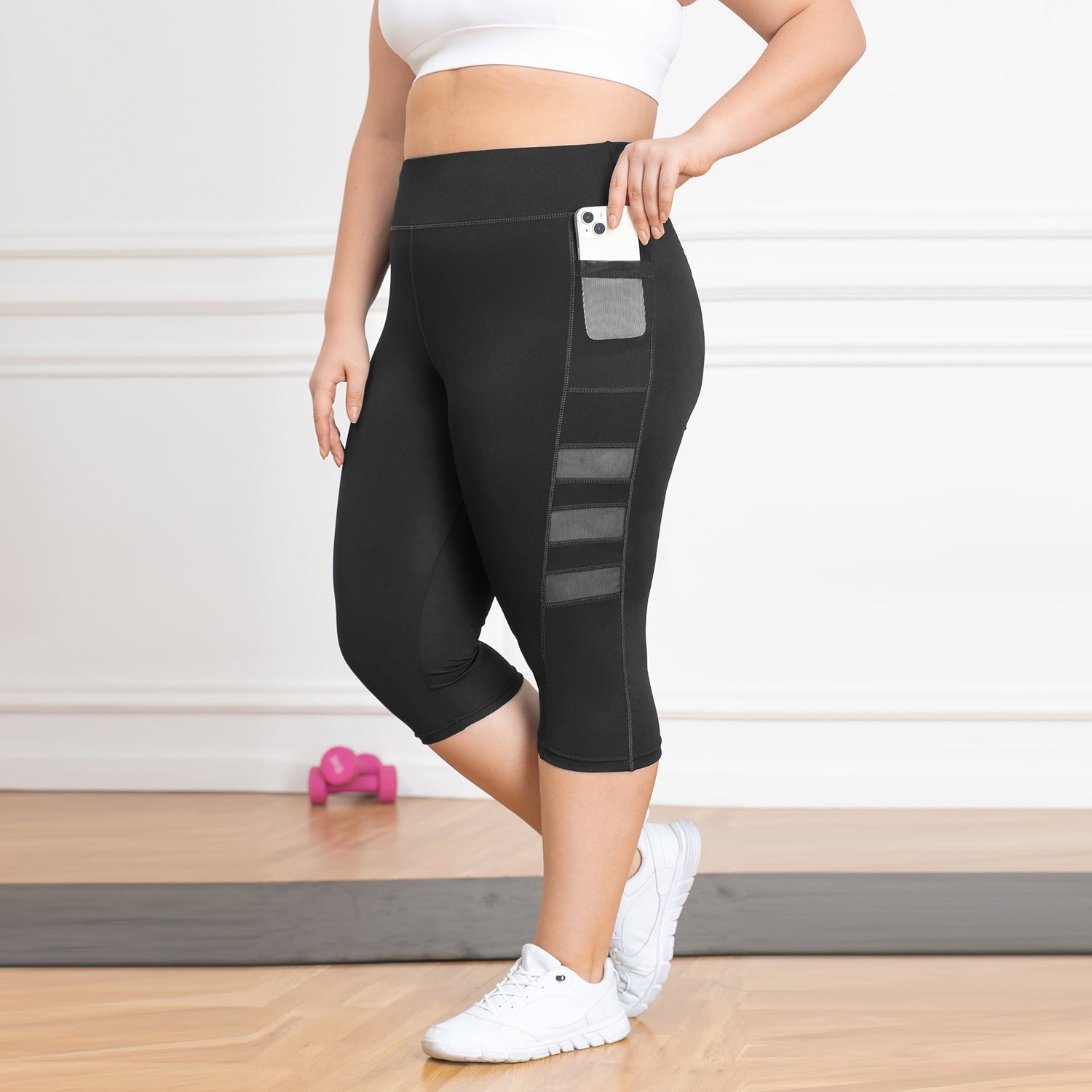 Person wearing black leggings with pocket details on a light wooden floor.