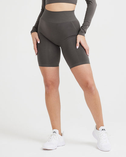 Person wearing dark gray athletic shorts and a long-sleeve crop top on a white background