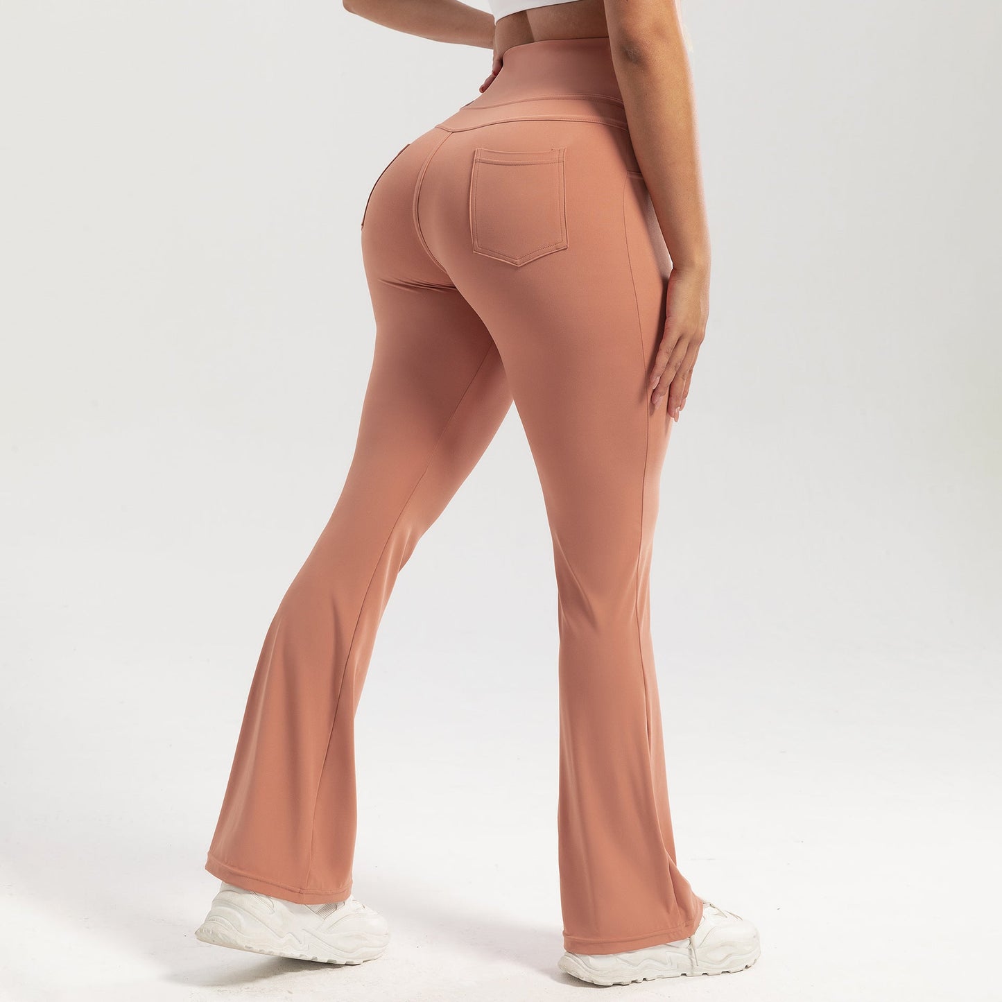 Person wearing peach-colored flared pants on a white background