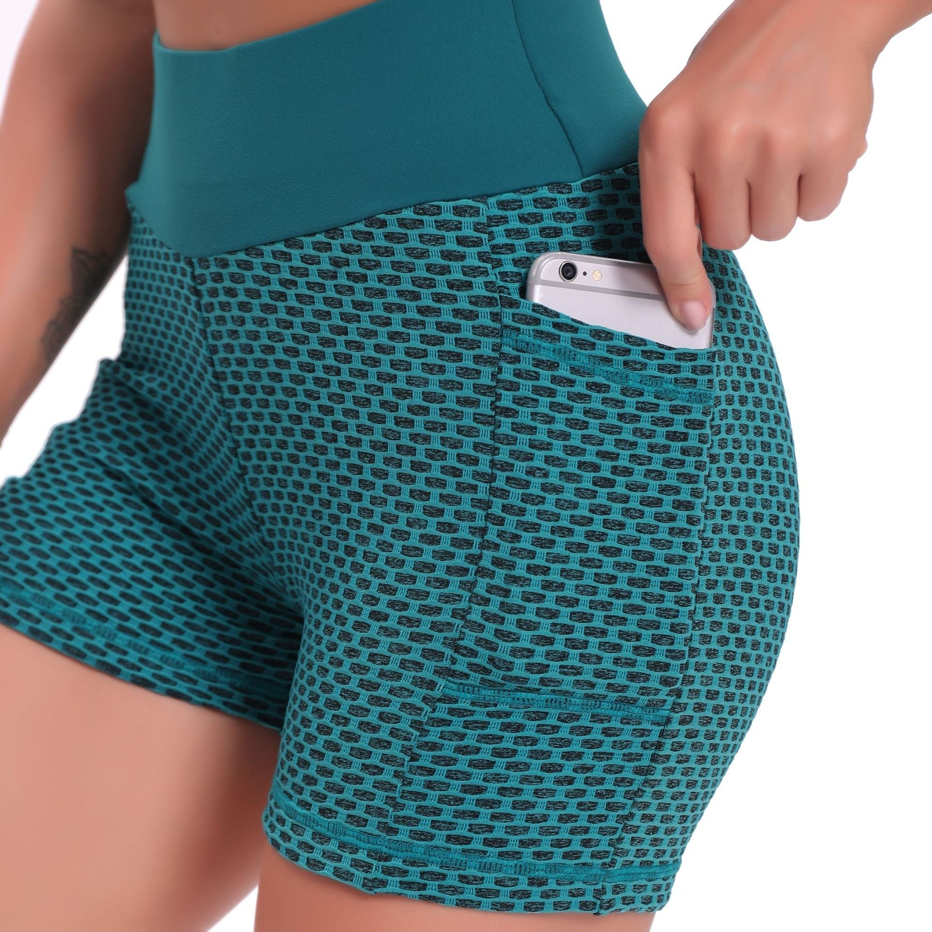 Teal patterned shorts with a pocket holding a phone on a white background