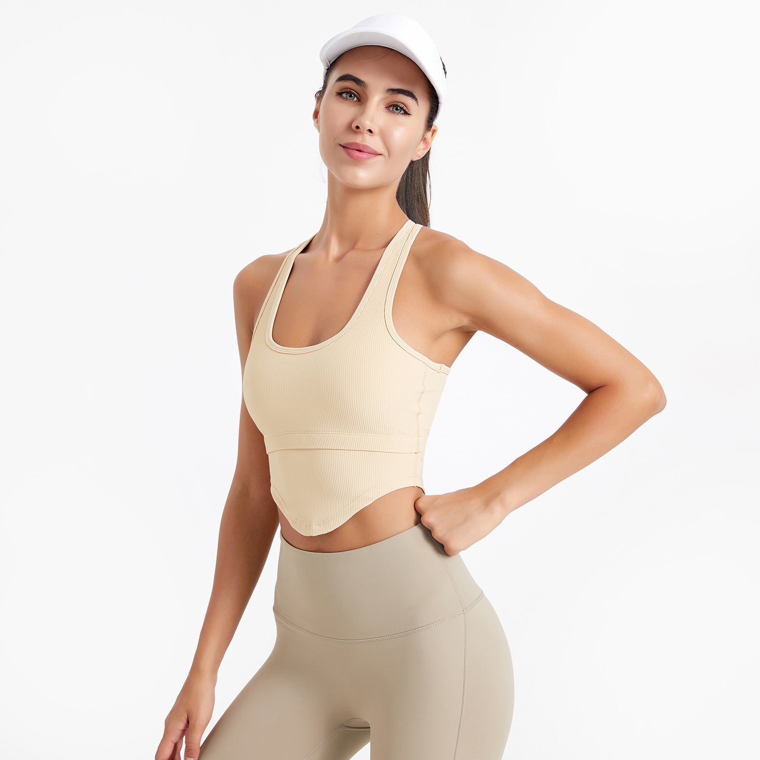 Woman wearing a beige sports bra and leggings on a white background