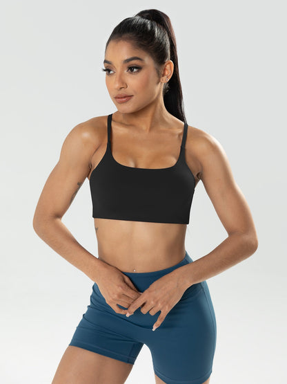 Woman wearing a black sports bra and blue shorts on a light gray background