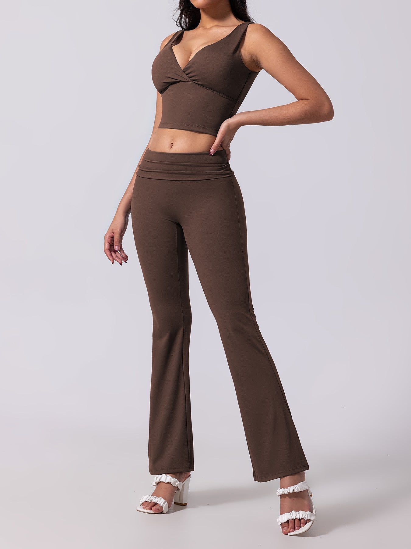 Woman wearing a brown outfit with a top and flared pants on a white background