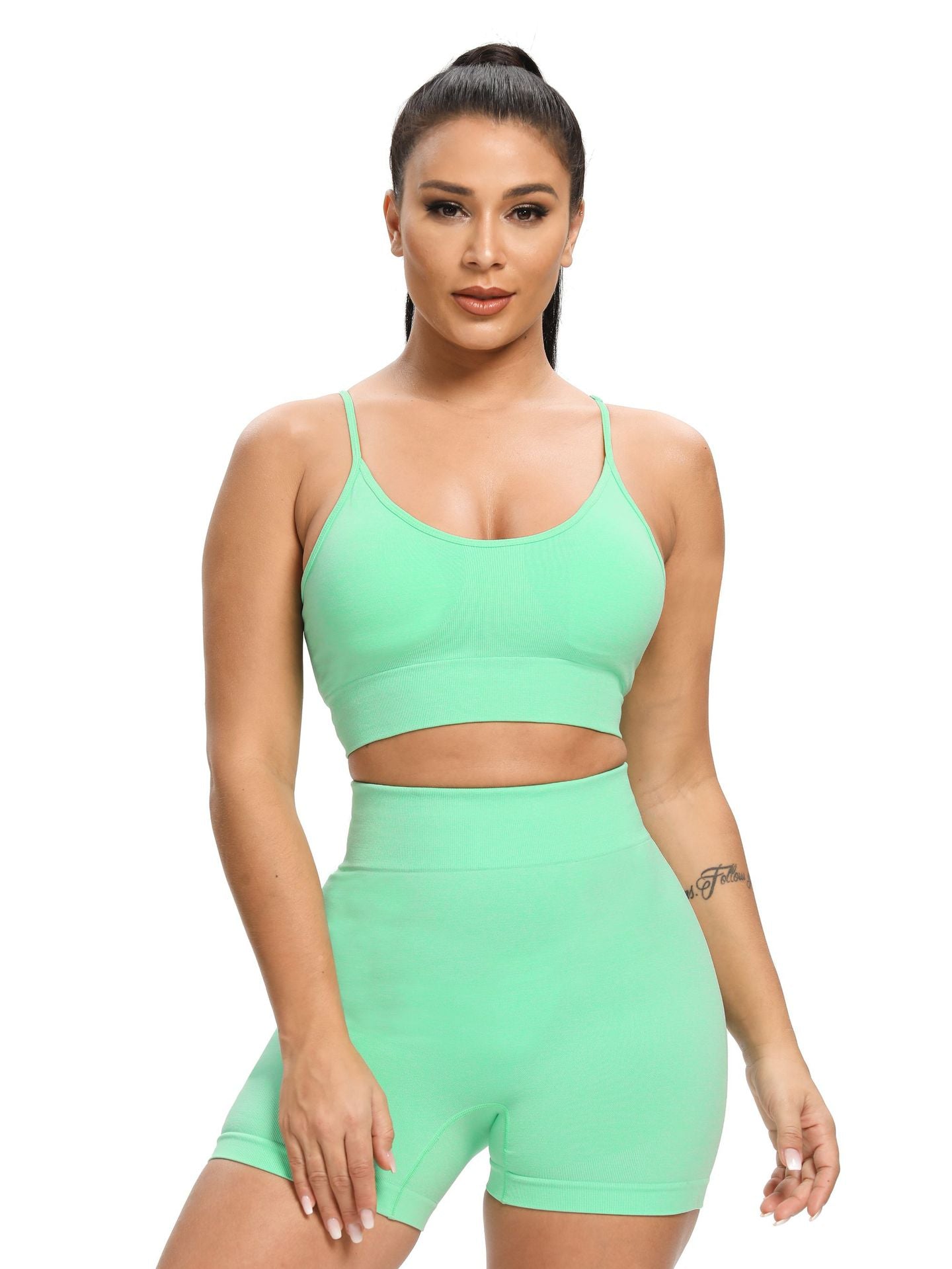 Woman wearing a green sports bra and shorts set on a white background