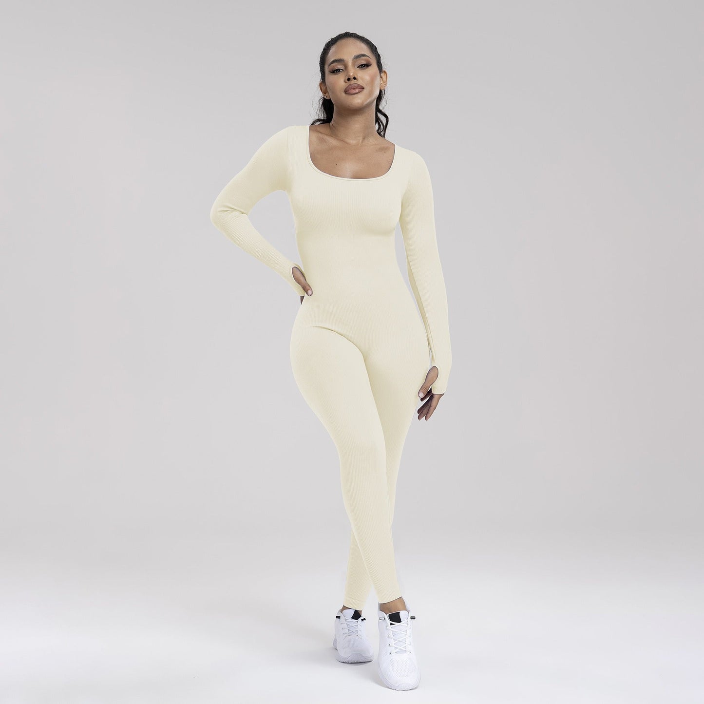 Woman wearing a light yellow long-sleeve top and leggings set on a plain background