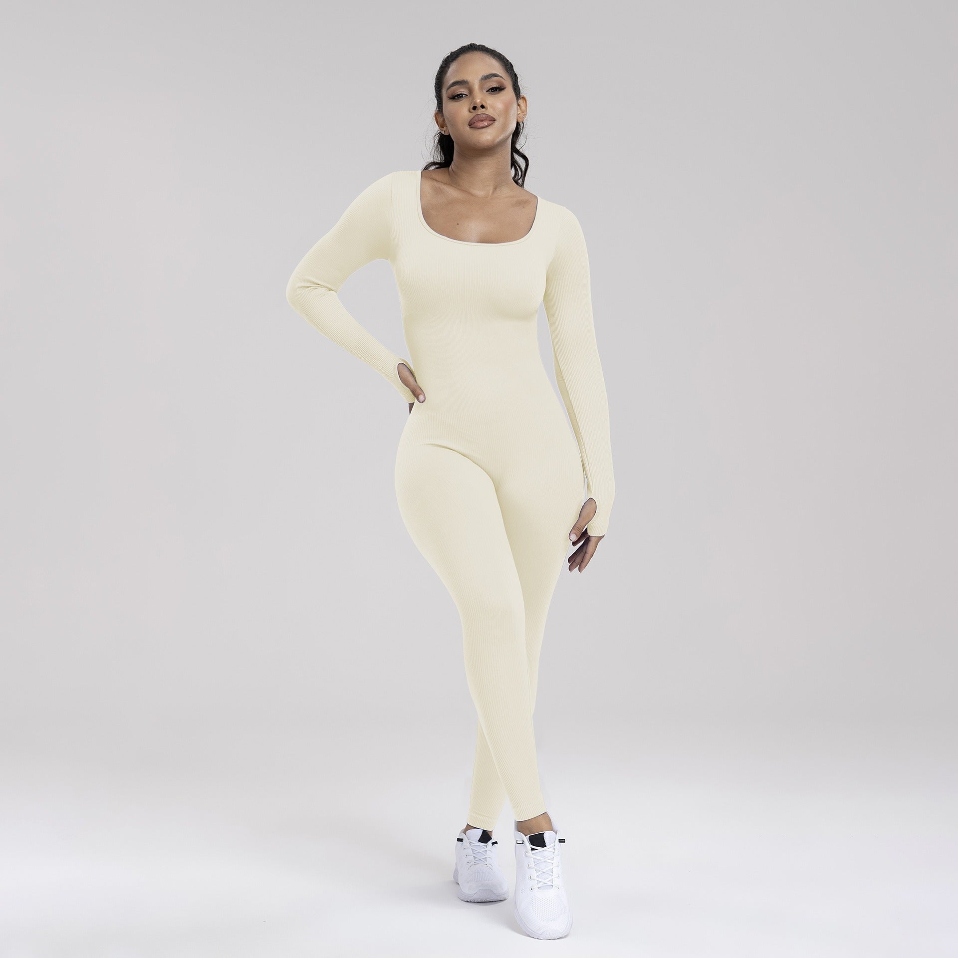 Woman wearing a light yellow long-sleeve top and leggings set on a plain background