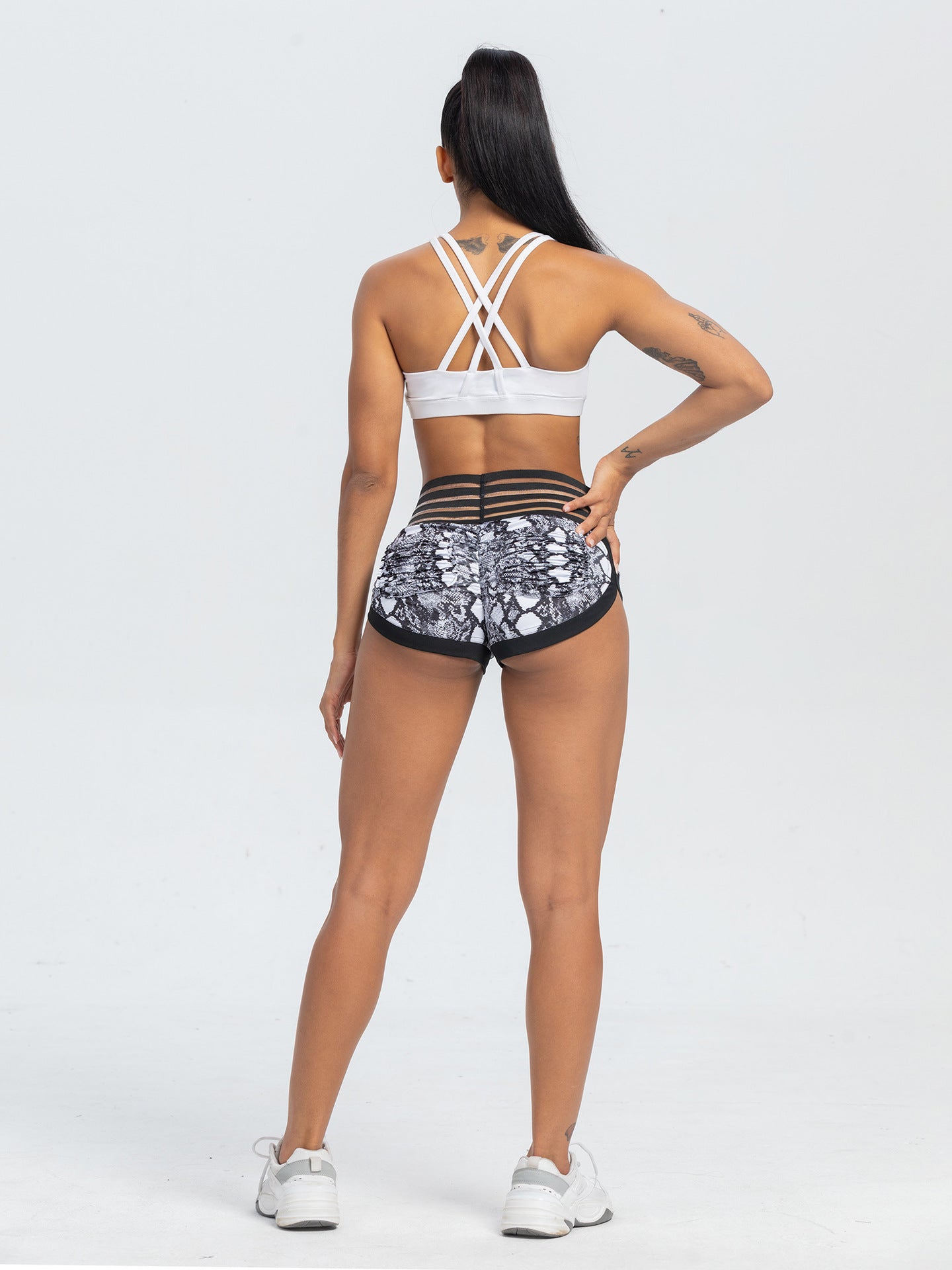 Woman wearing a white sports bra and patterned shorts on a white background