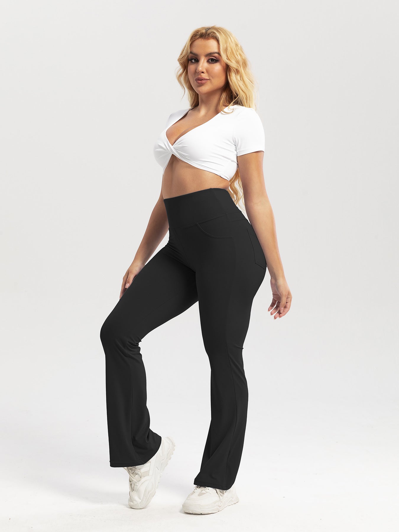 Woman wearing a white top and black pants on a plain background