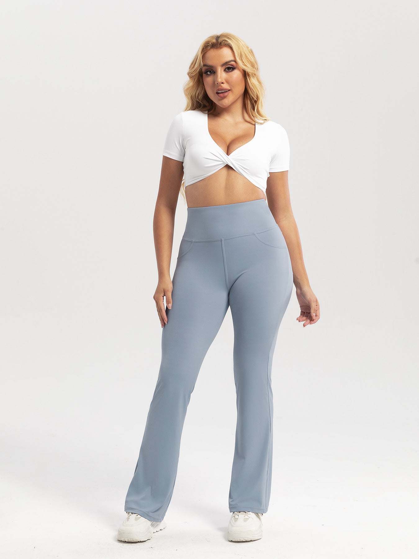 Woman wearing a white top and light blue high-waisted pants on a white background