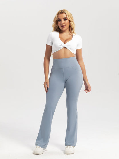 Woman wearing a white top and light blue high-waisted pants on a white background