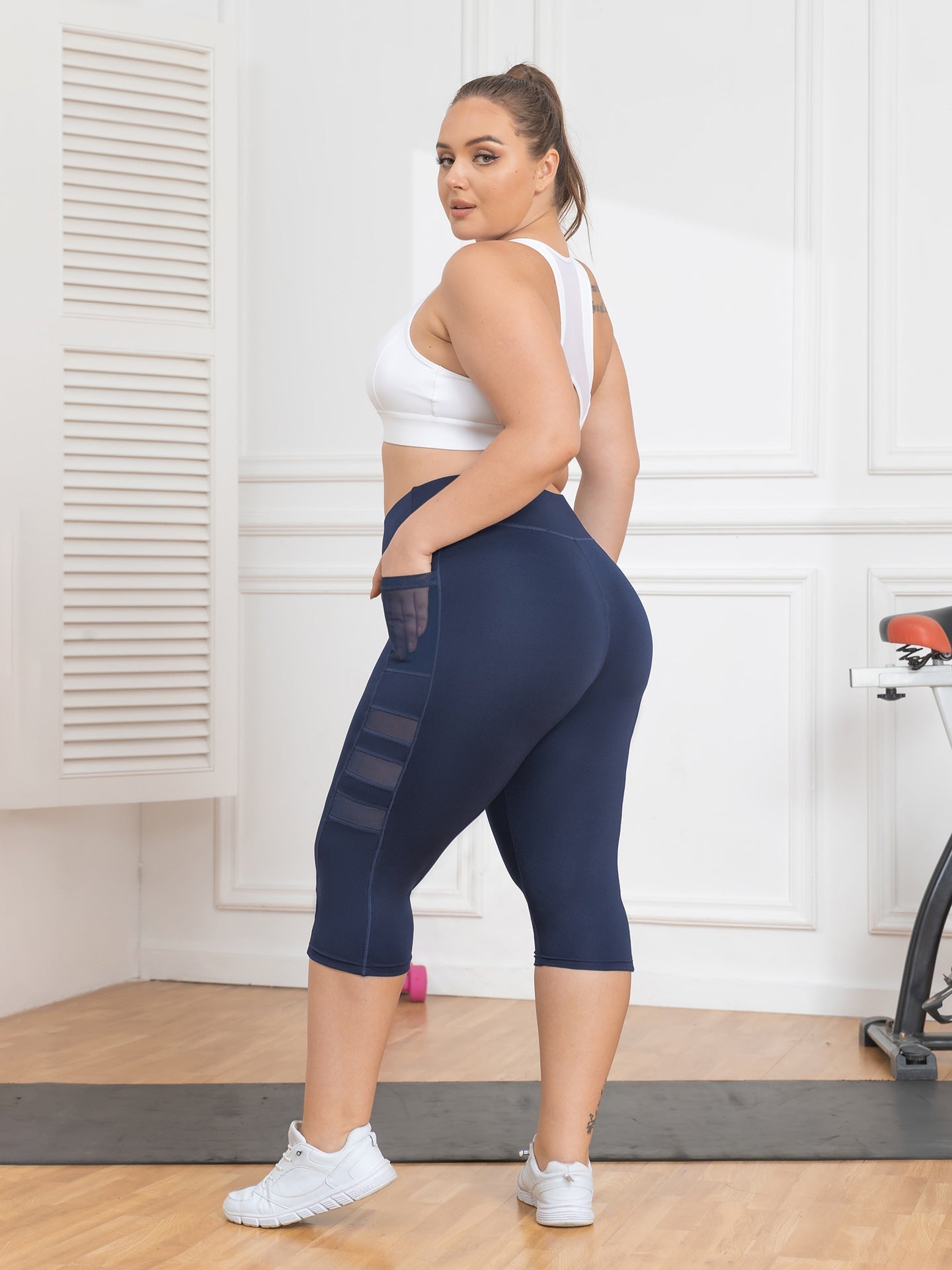 Woman wearing navy leggings with mesh panels in a home setting