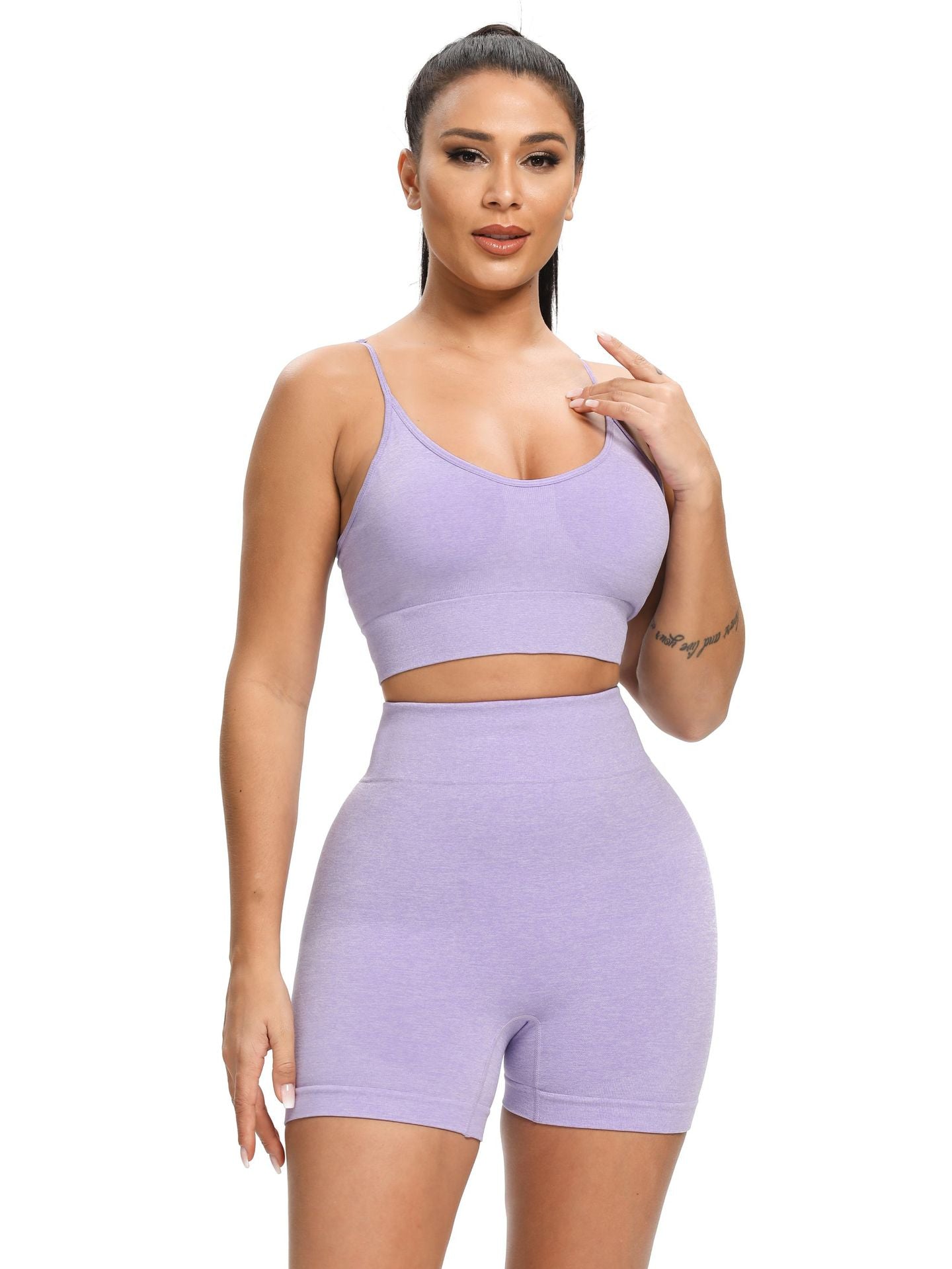 Woman wearing a purple sports bra and shorts set on a white background