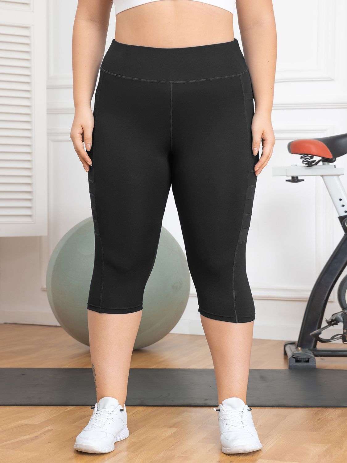 Person wearing black capri leggings in a gym setting